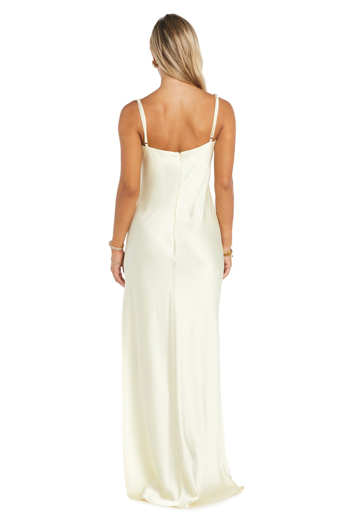 Woman with back to camera wears the Morgan 10040N: an empire-waist, long cream satin prom dress with thin straps and sleeveless design.